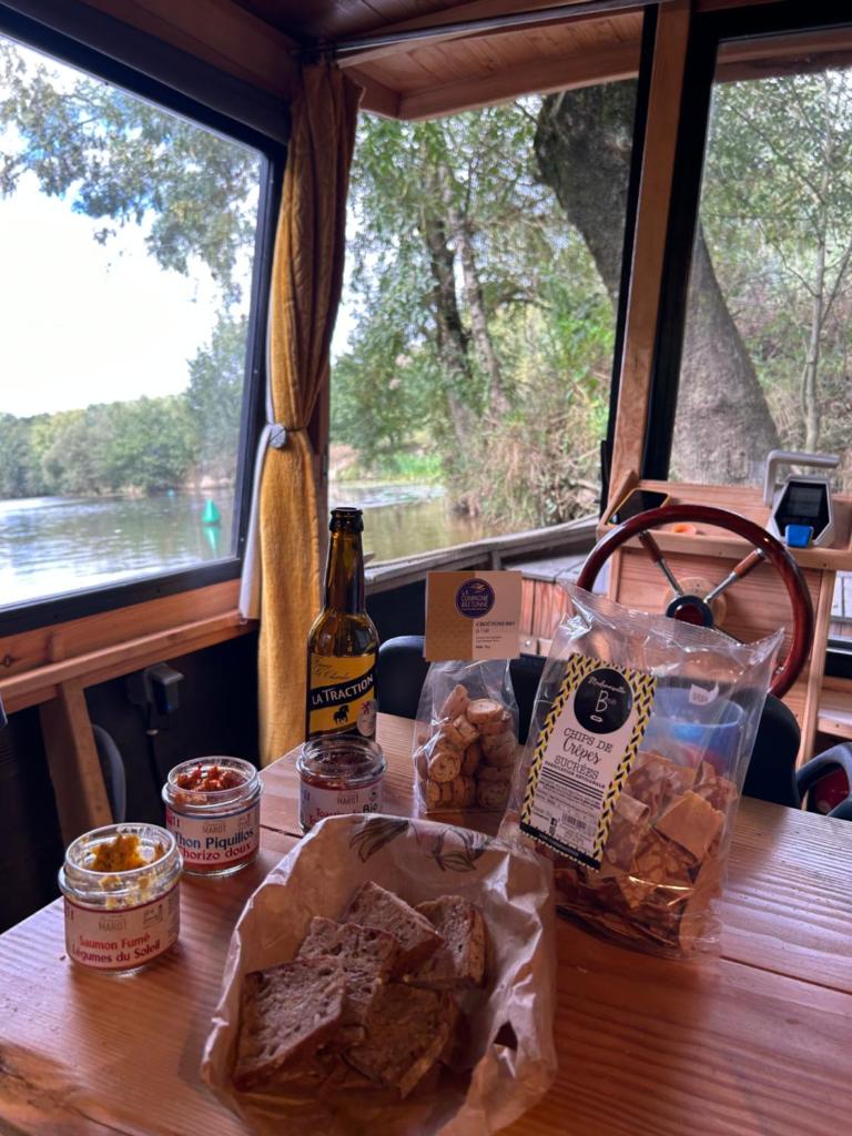 - une table avec deux sacs de pain et une bouteille de bière dans l'établissement Patouillet bateau naviguant, à Saint-Vincent-sur-Oust