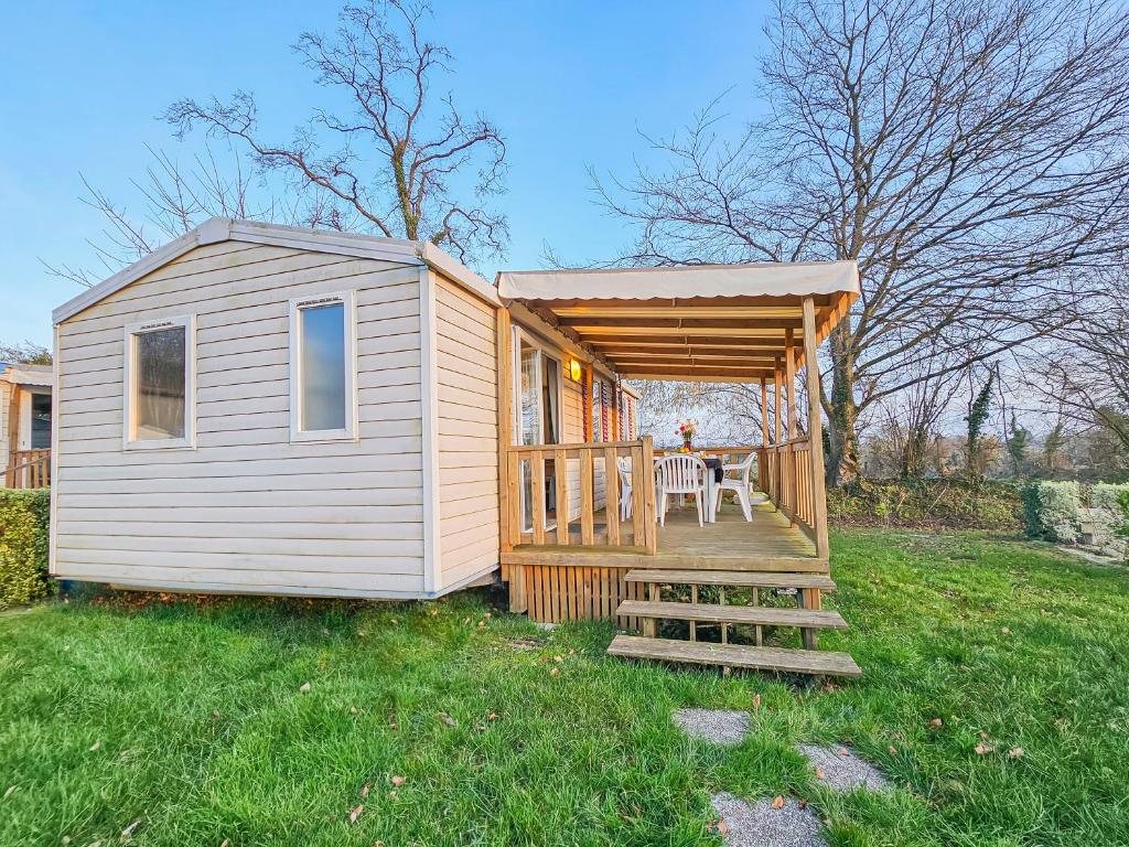 une petite maison avec une terrasse couverte et une table dans l'établissement Loc Jade, à Litteau