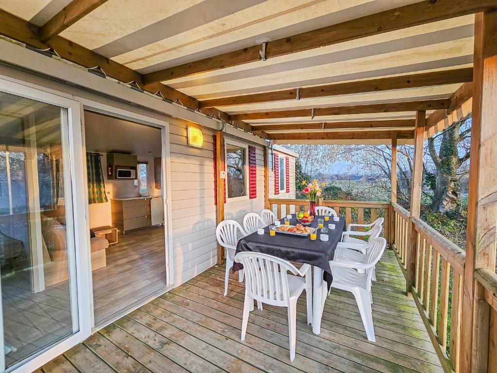 - une terrasse couverte avec une table et des chaises dans l'établissement Loc Jade, à Litteau