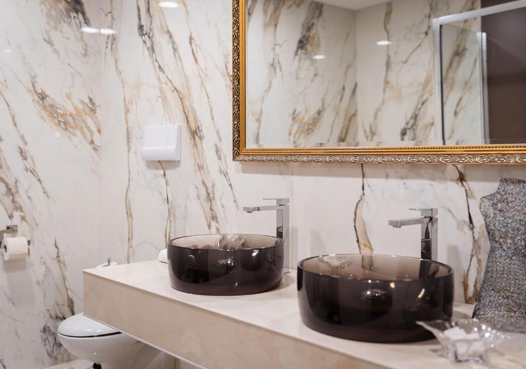 une salle de bains avec deux lavabos noirs sur un comptoir dans l'établissement Hotel Meridiana, à Paestum