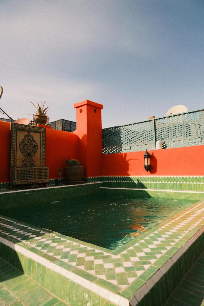 une piscine d'eau en face d'un bâtiment dans l'établissement Riad Orange, à Marrakech
