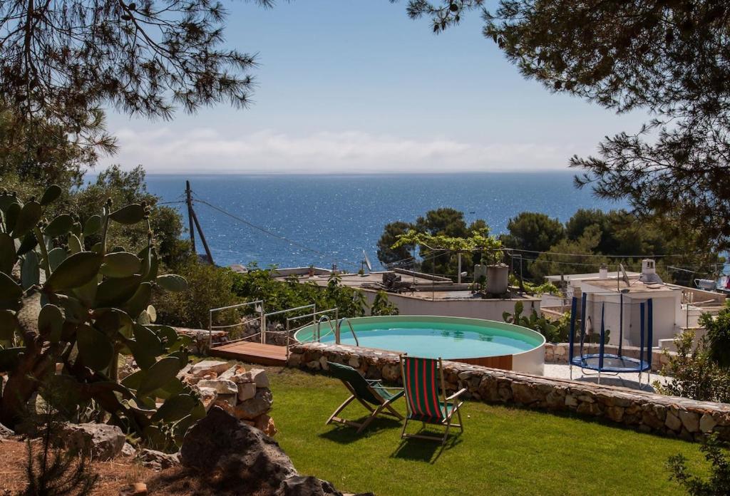 une piscine avec deux chaises et l'océan dans l'établissement Villa Loreta LUXURY TOP FLOOR, à Gagliano del Capo