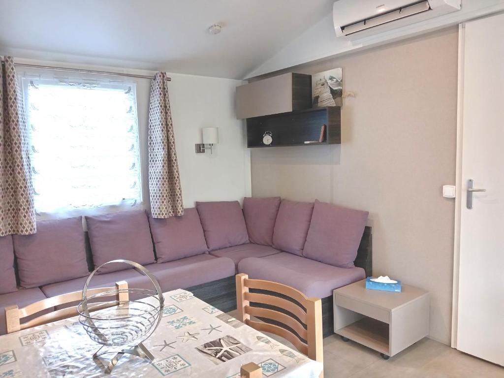 un salon avec un canapé violet et une table dans l'établissement MH 468 LUMINOSA 3ch dont 1 suite parentale et 2sdb proche des activités dans camping 4 étoiles, à Saint-Julien-en-Born 6 autres photos