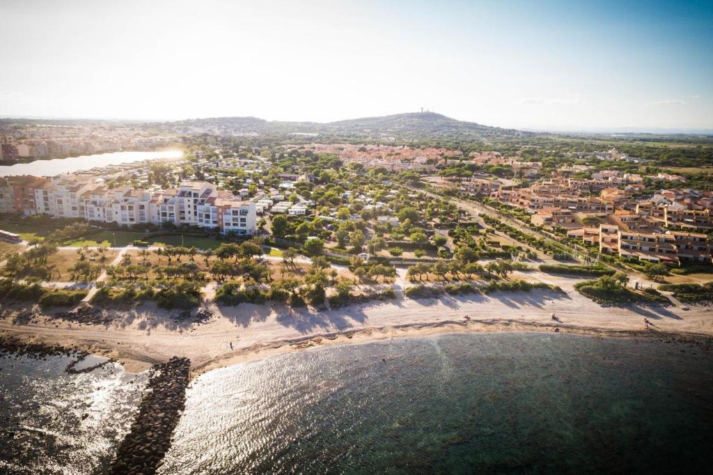une vue aérienne d'une plage avec des bâtiments et l'eau dans l'établissement Camping de la Clape Village - Maeva, au Cap d'Agde