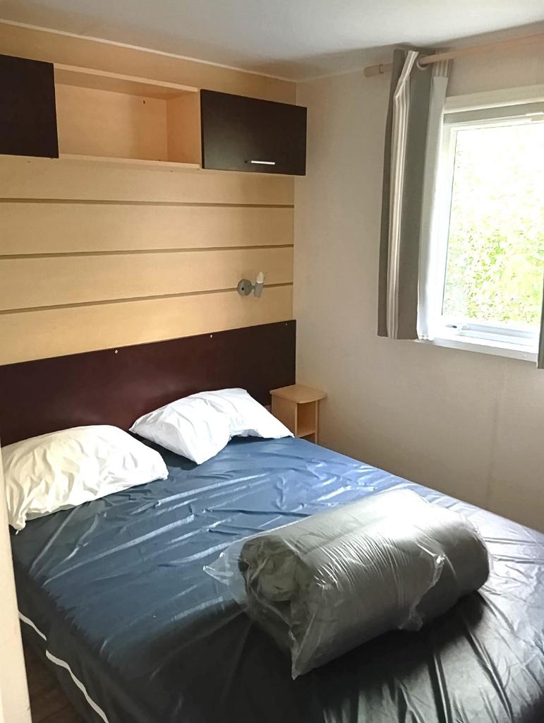 une chambre avec un lit bleu avec une fenêtre dans l'établissement Mobil-Home Provence, à Cheval-Blanc