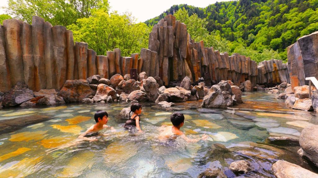 3 enfants dans une piscine d'eau dans un zoo dans l'établissement Sounkyo Kankou Hotel, à Kamikawa