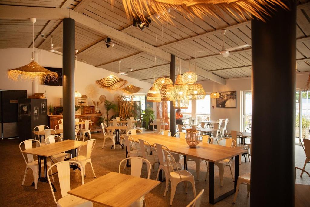 un restaurant avec des tables en bois et des chaises blanches dans l'établissement Camping Château de Galaure, à Châteauneuf-de-Galaure