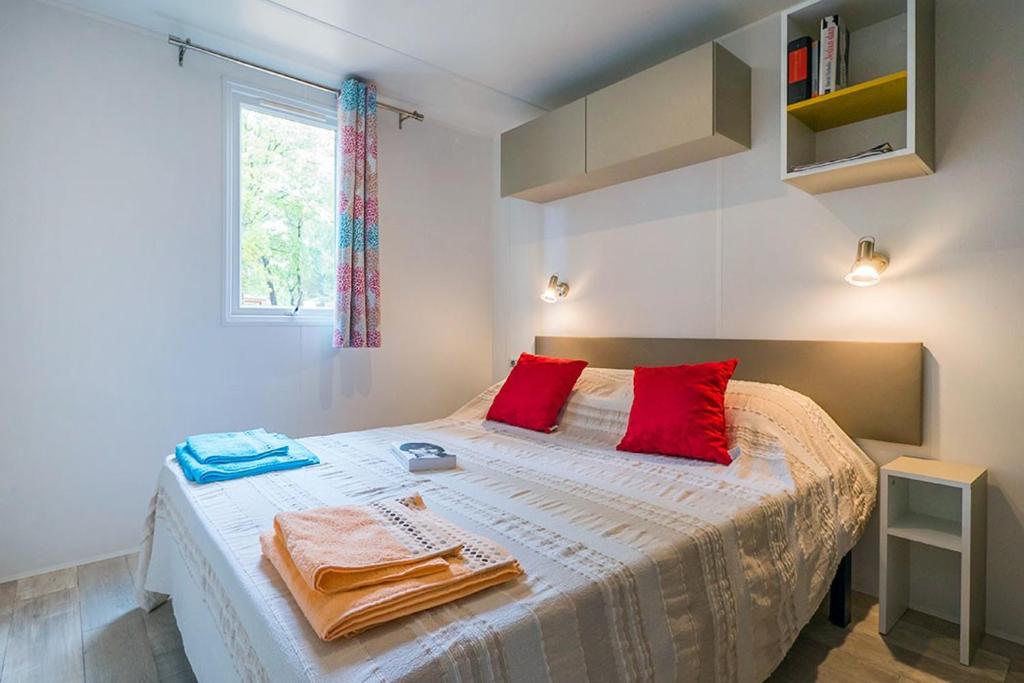 une chambre avec un lit avec des oreillers rouges et une fenêtre dans l'établissement Camping Château de Galaure, à Châteauneuf-de-Galaure