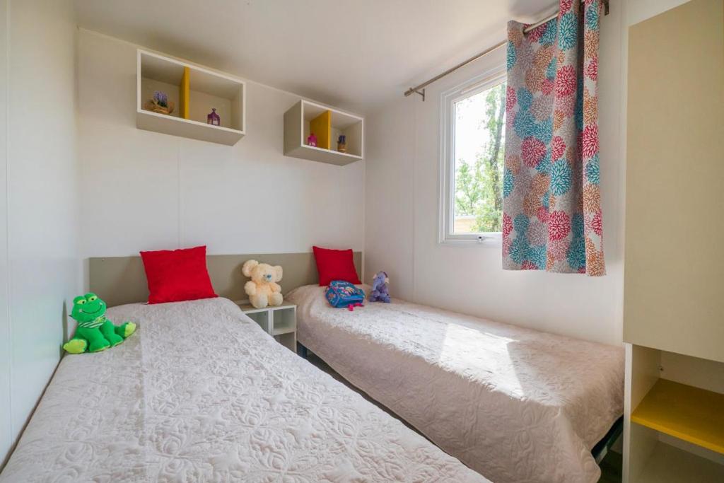 deux lits dans une petite pièce avec une fenêtre dans l'établissement Camping Château de Galaure, à Châteauneuf-de-Galaure 22 autres photos