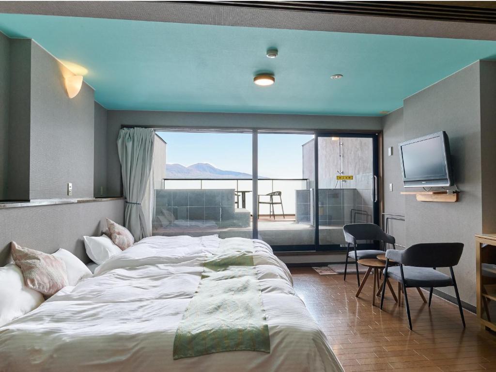 une chambre avec un grand lit et une grande fenêtre dans l'établissement Yumeoi-so, à Aso