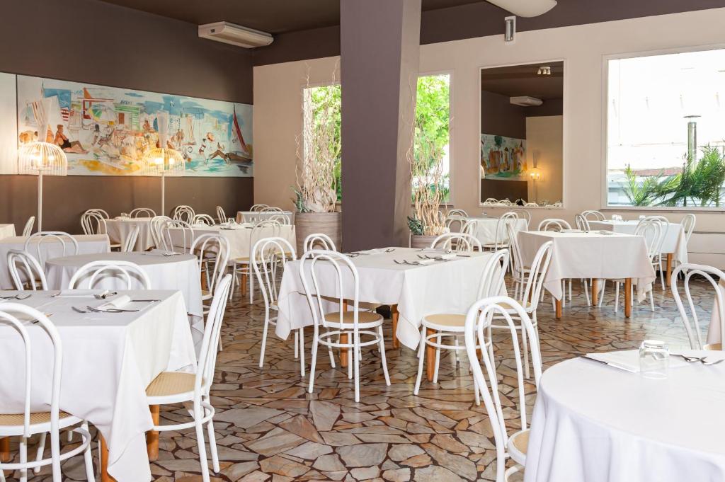 une salle à manger avec des tables et des chaises blanches dans l'établissement HOTEL TRIONFAL - Fronte Mare - Vicinissimi al Centro, à Milano Marittima