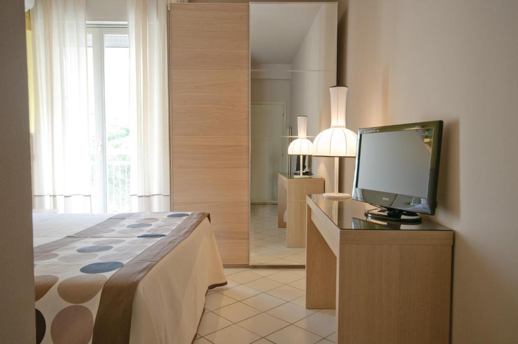 une chambre avec un lit et une télévision sur une commode dans l'établissement HOTEL TRIONFAL - Fronte Mare - Vicinissimi al Centro, à Milano Marittima