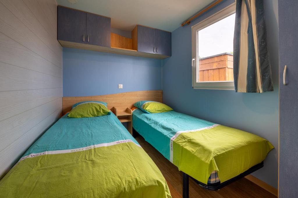 deux lits dans une petite pièce avec une fenêtre dans l'établissement Mobilhome 6 pers - Piscine, à Saint-Gildas-de-Rhuys 17 autres photos