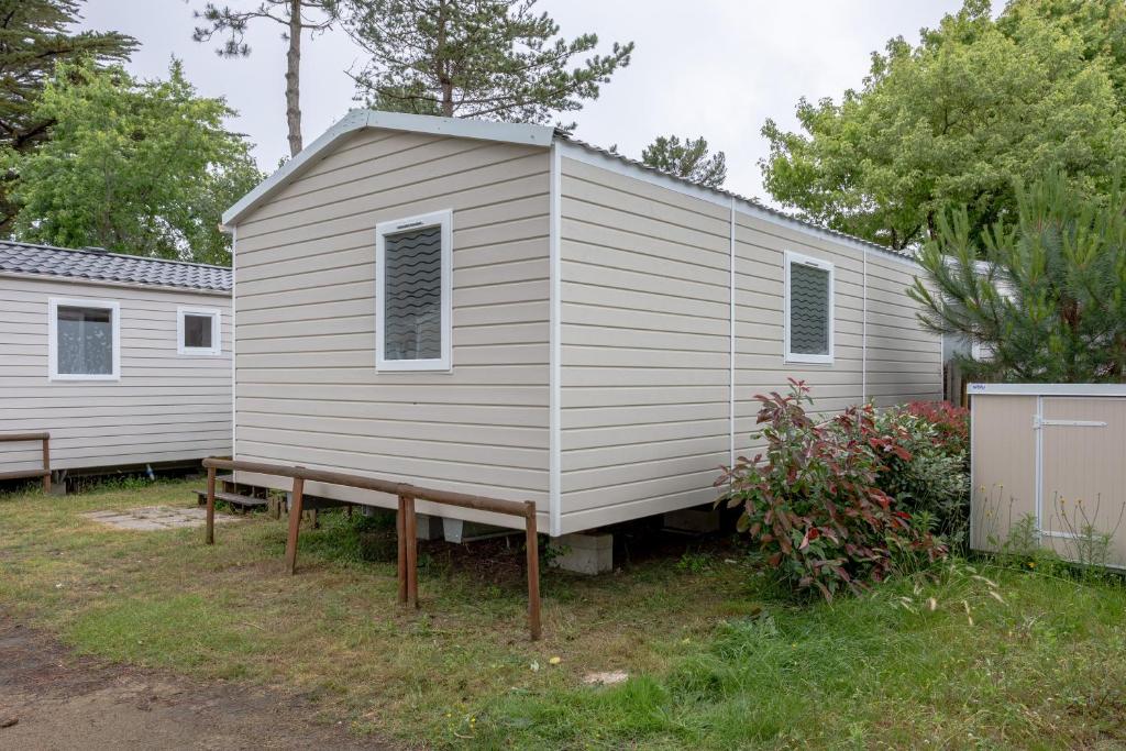une grande maison blanche avec un banc dans une cour dans l'établissement Mobil-home 2 chambres - D, à Saint-Jean-de-Monts