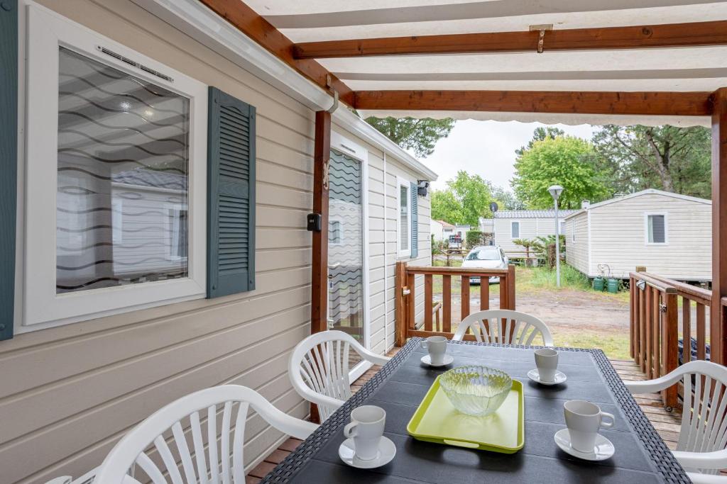 un patio avec une table et des chaises sur un porche dans l'établissement Mobil-home 2 chambres - D, à Saint-Jean-de-Monts