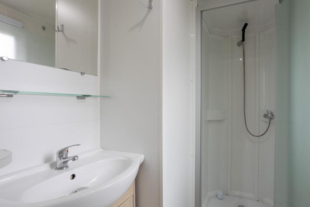 une salle de bain blanche avec un lavabo et une douche dans l'établissement Mobil-home 2 chambres - D, à Saint-Jean-de-Monts