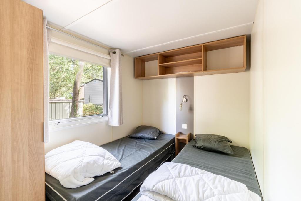 une chambre avec deux lits et une fenêtre dans l'établissement Mobil home 8 personnes, à Saint-Brévin-les-Pins