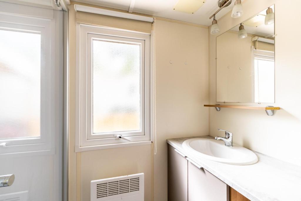une salle de bain avec un lavabo et une fenêtre dans l'établissement Mobil home 8 personnes, à Saint-Brévin-les-Pins