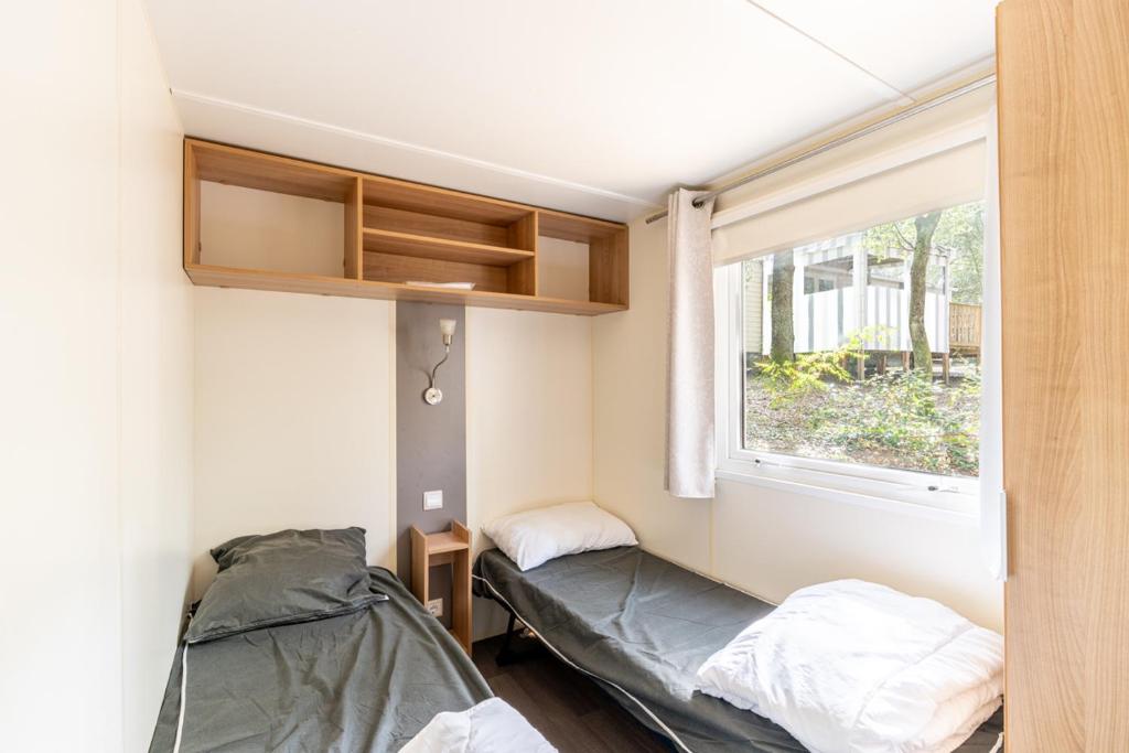 une petite chambre avec deux lits et une fenêtre dans l'établissement Mobil home 8 personnes, à Saint-Brévin-les-Pins 13 autres photos