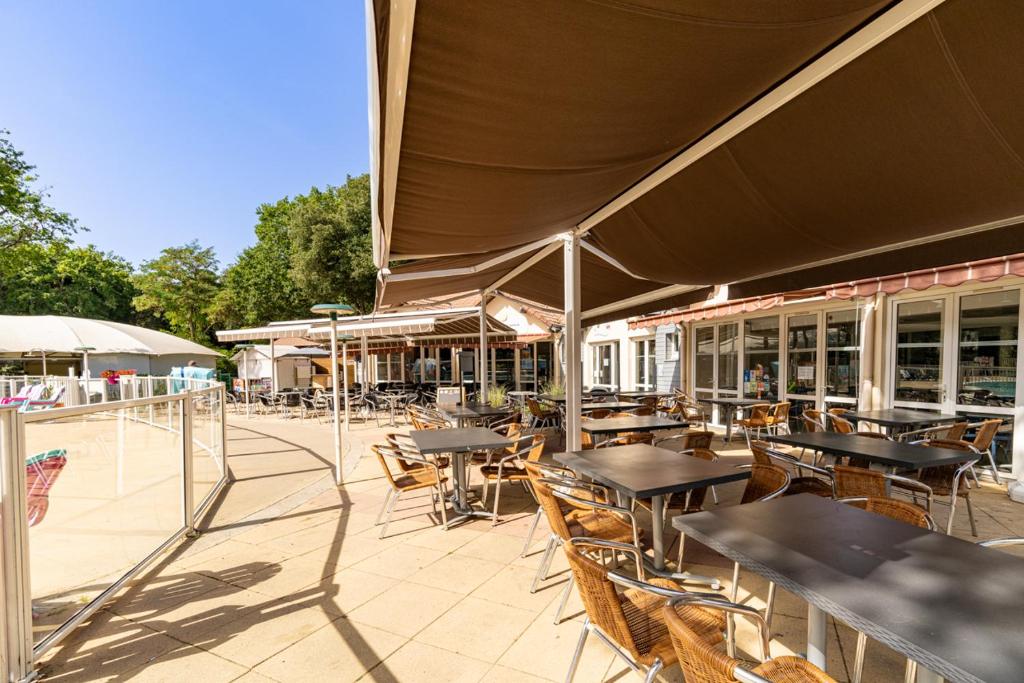 un patio extérieur avec tables, chaises et fenêtres dans l'établissement Mobil home 8 personnes, à Saint-Brévin-les-Pins