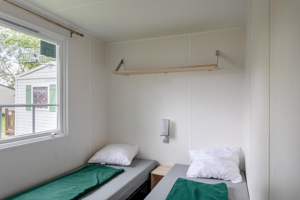 deux lits dans une petite pièce avec une fenêtre dans l'établissement Mobil-home, à Angles