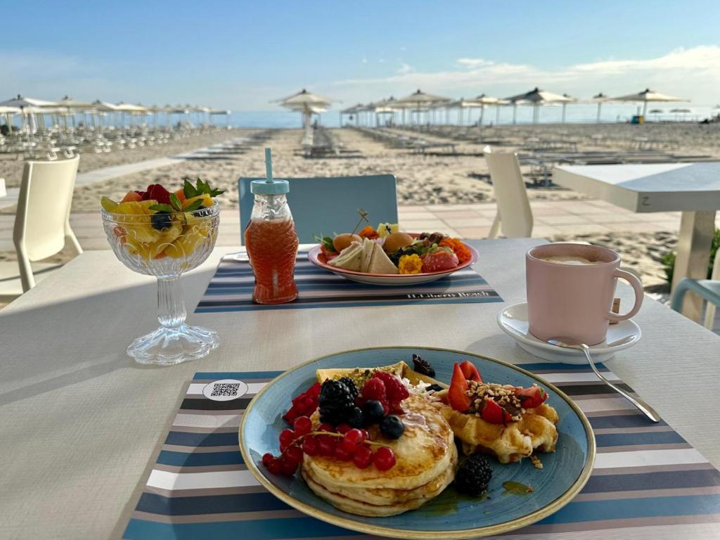 une table avec une assiette de petit-déjeuner sur la plage dans l'établissement Hotel Liberty Beach - Parking & Beach, à Riccione