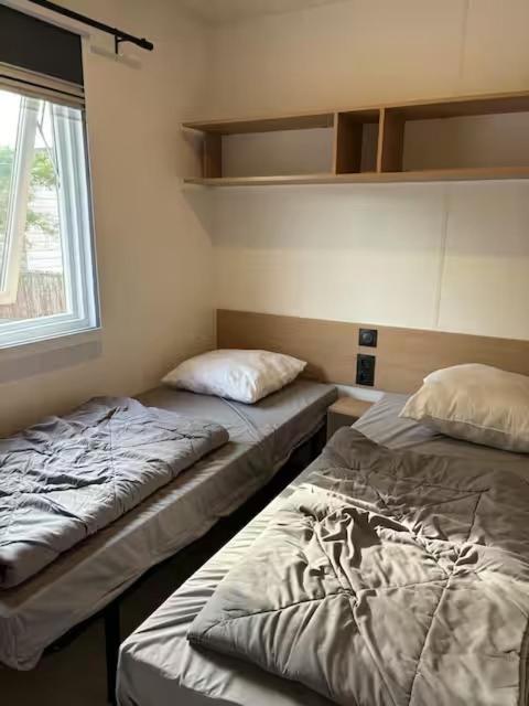 deux lits assis dans une pièce avec une fenêtre dans l'établissement Camping 5 Les Dunes Mobil-Home 6Pers, à Torreilles
