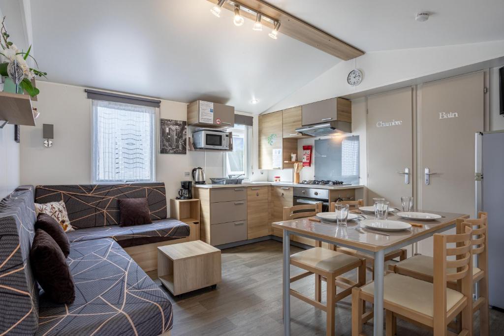 une cuisine et un salon avec un canapé et une table dans l'établissement Mobil-home 2 chambres - C, à Saint-Jean-de-Monts
