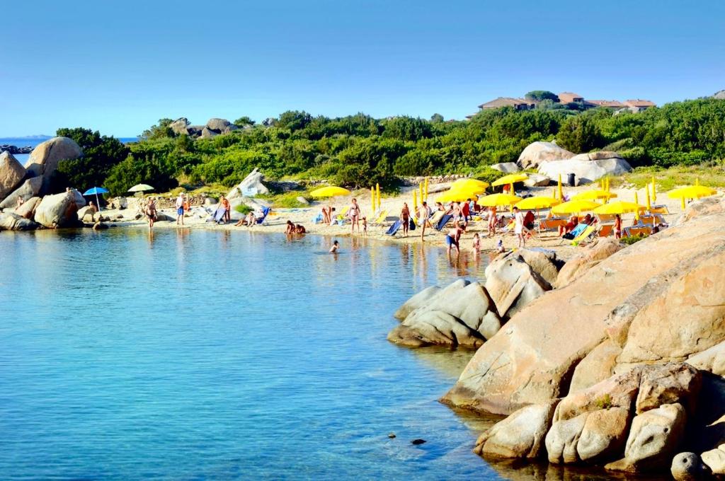 un groupe de personnes sur une plage avec des parasols jaunes dans l'établissement Residence with private beach in Marinella, à Marinella 13 autres photos