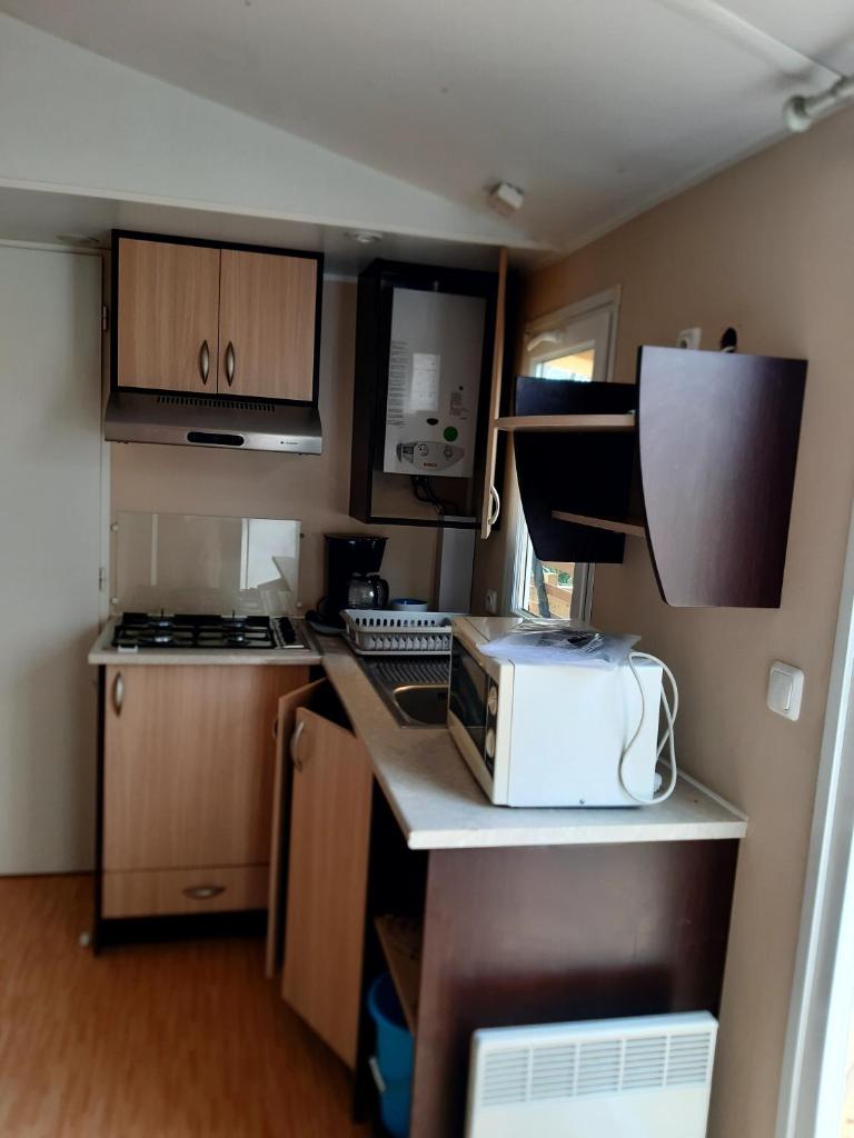 une petite cuisine avec une cuisinière et un micro-ondes dans l'établissement Mobil-home - Le 147 aux Iscles, à La Roque-dʼAnthéron