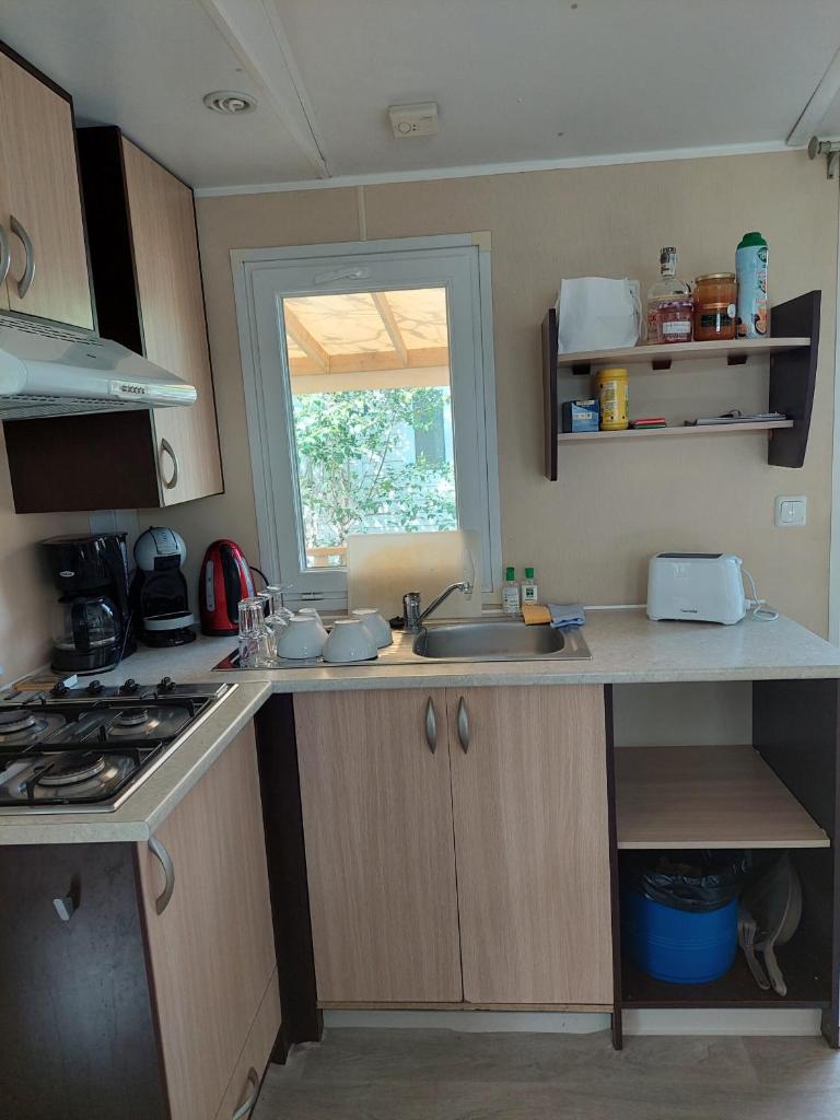 une petite cuisine avec un évier et une fenêtre dans l'établissement Mobil-home Le 154 aux Iscles, à La Roque-dʼAnthéron