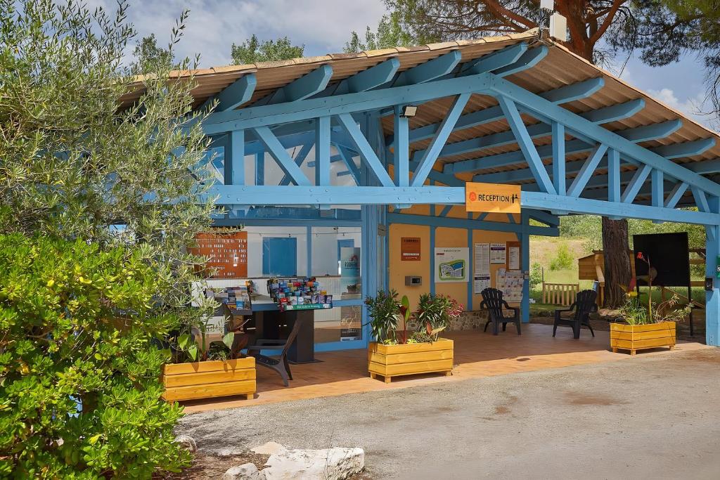 un bâtiment bleu avec des plantes devant dans l'établissement Mobil-home Le 154 aux Iscles, à La Roque-dʼAnthéron
