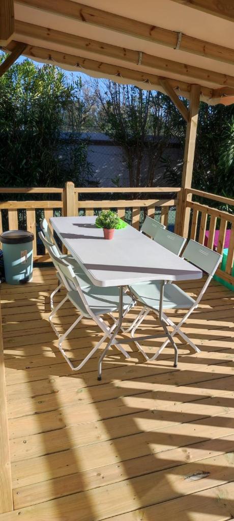 une table et des chaises blanches sur une terrasse en bois dans l'établissement mobil home chaleureux et idyllique, à Lattes
