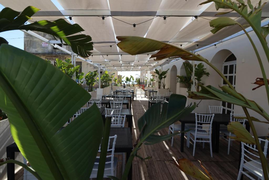 un restaurant avec des tables, des chaises et des plantes dans l'établissement Hotel Noto Marina Vista Mare, à Noto Marina