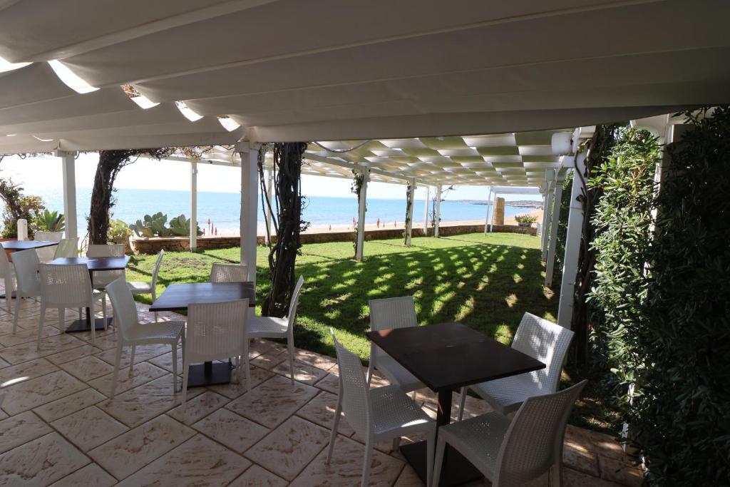 une terrasse avec des tables et des chaises et la plage dans l'établissement Hotel Noto Marina Vista Mare, à Noto Marina 12 autres photos