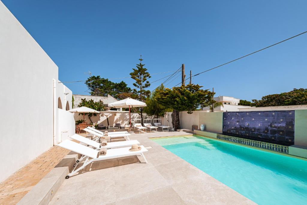 une piscine avec des chaises longues et une piscine dans l'établissement HelloApulia Villa Pool and Beach - 150mt from the sea, à San Foca