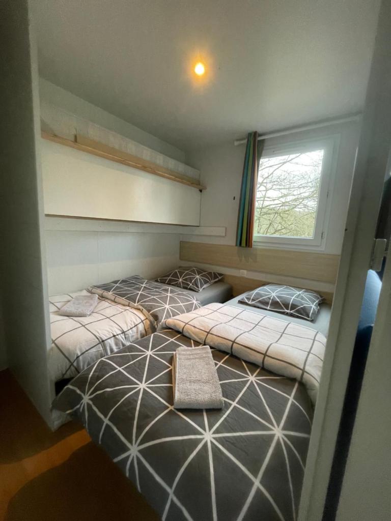 deux lits dans une petite pièce avec une fenêtre dans l'établissement logement au coeur de la nature, à Le Grand-Lucé