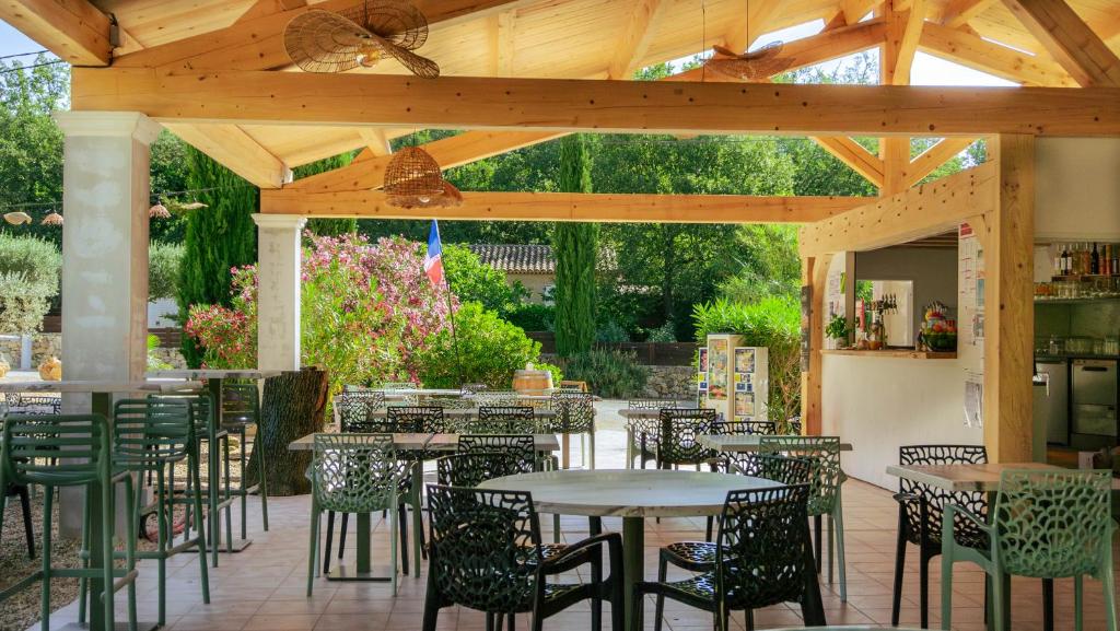 un patio avec tables et chaises sous une pergola en bois dans l'établissement Camping Domaine Villa Verde, à Callas