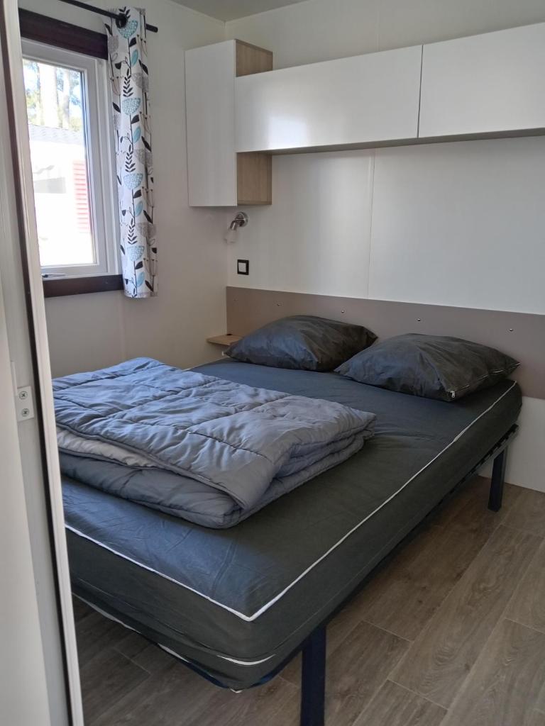 un grand lit dans une chambre avec une fenêtre dans l'établissement MH 495 SALSA 2 chambres et 1 salle de bain dans camping 4 étoiles, à Saint-Julien-en-Born