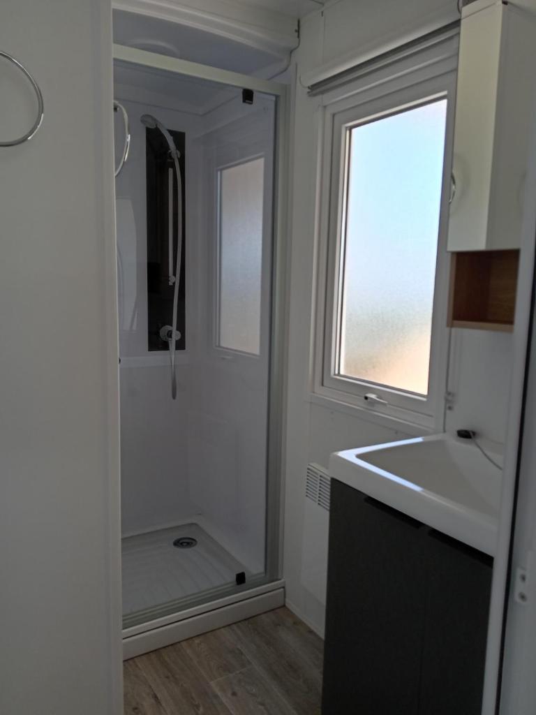 une petite salle de bain avec un lavabo et une fenêtre dans l'établissement MH 495 SALSA 2 chambres et 1 salle de bain dans camping 4 étoiles, à Saint-Julien-en-Born