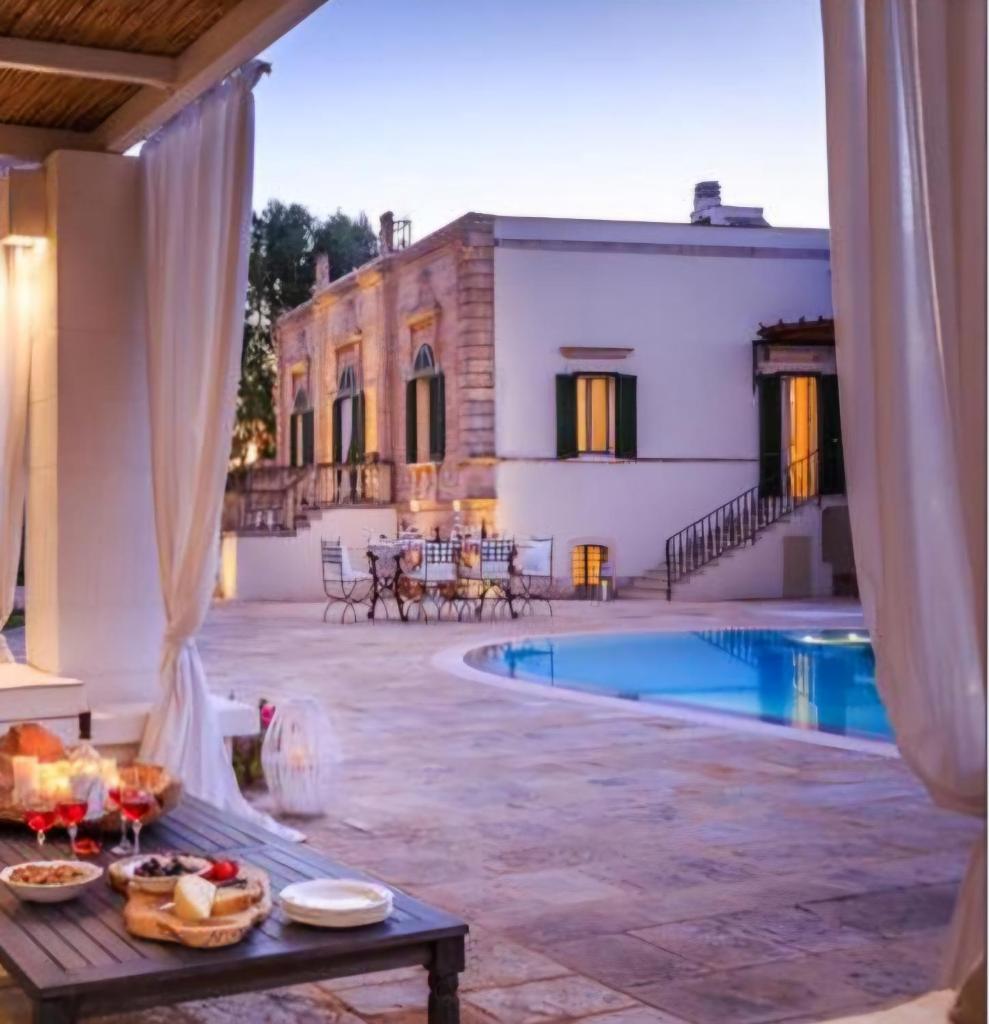 un patio avec une table et une piscine dans l'établissement Villa Favorita Luxury - Italia Monopoli Puglia Trullo, à Monopoli