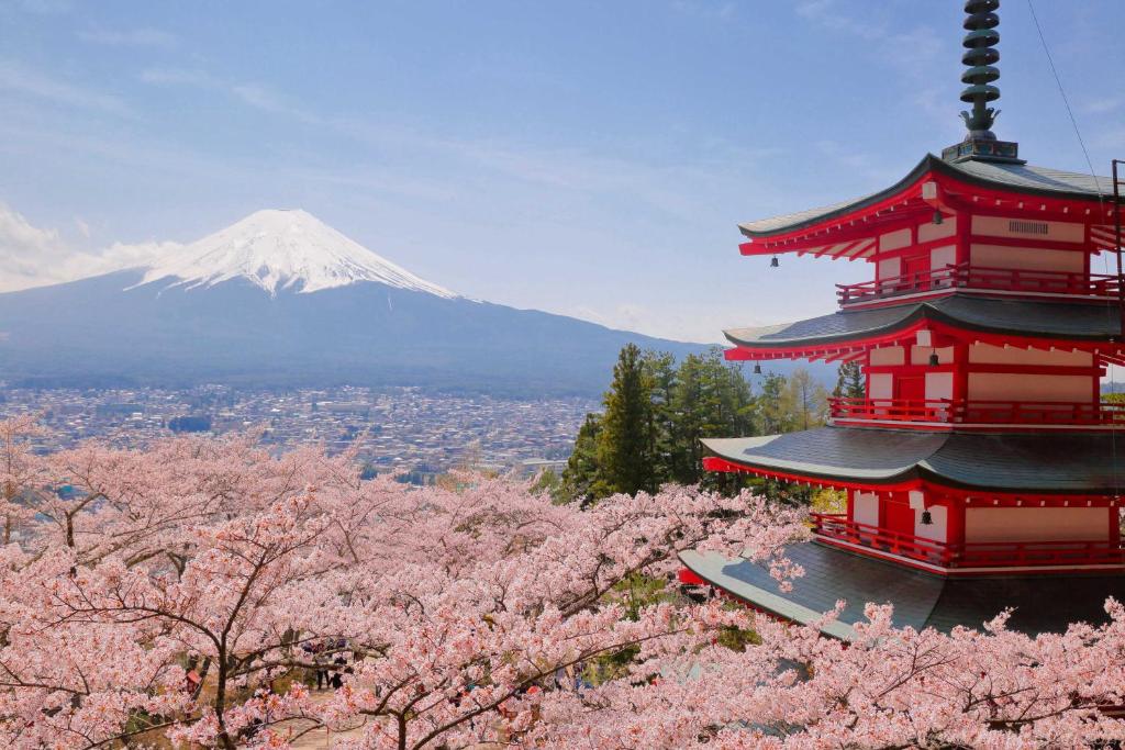 une pagode avec une montagne en arrière-plan plantée de cerisiers dans l'établissement Mt Fuji View and Private Sauna Ryokan Shizuku, à Yamanakako