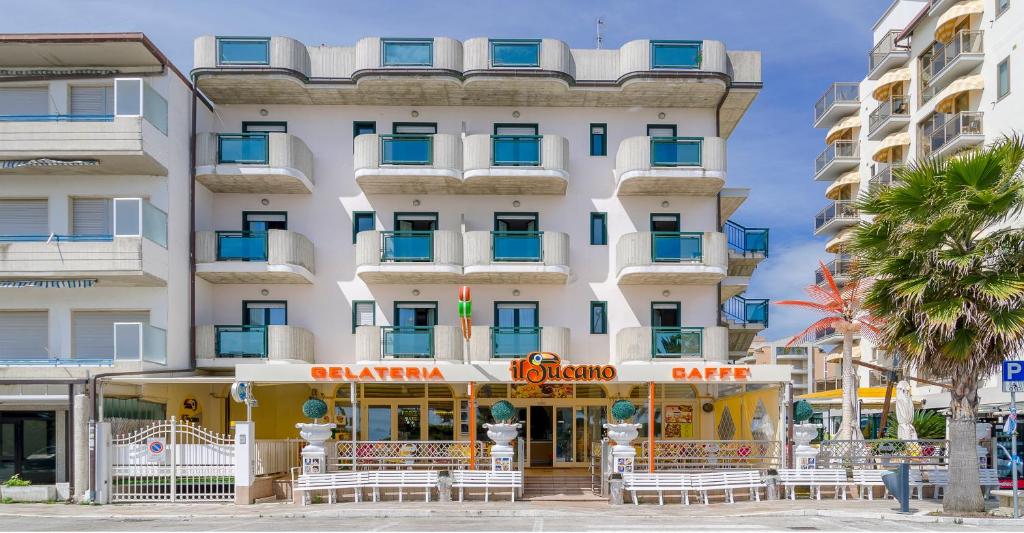 - un grand bâtiment blanc avec des chaises devant dans l'établissement Hotel Tassoni Maison, à Alba Adriatica
