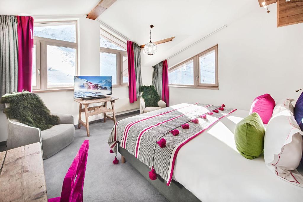une chambre avec un lit, une télévision et des fenêtres dans l'établissement Hotel Pashmina Le Refuge, à Val Thorens