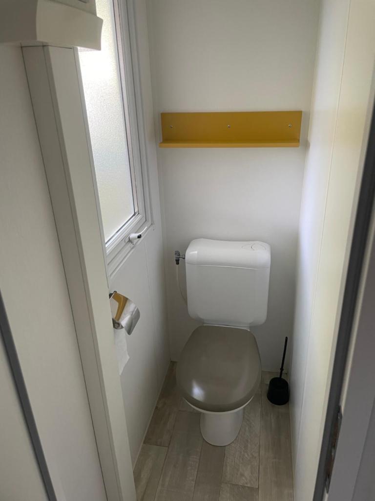 Elle comprend une petite salle de bains pourvue de toilettes et d'une fenêtre. dans l'établissement Camping Rivages des Landes Mobil-home climatisé et Tv, à Aureilhan 5 autres photos