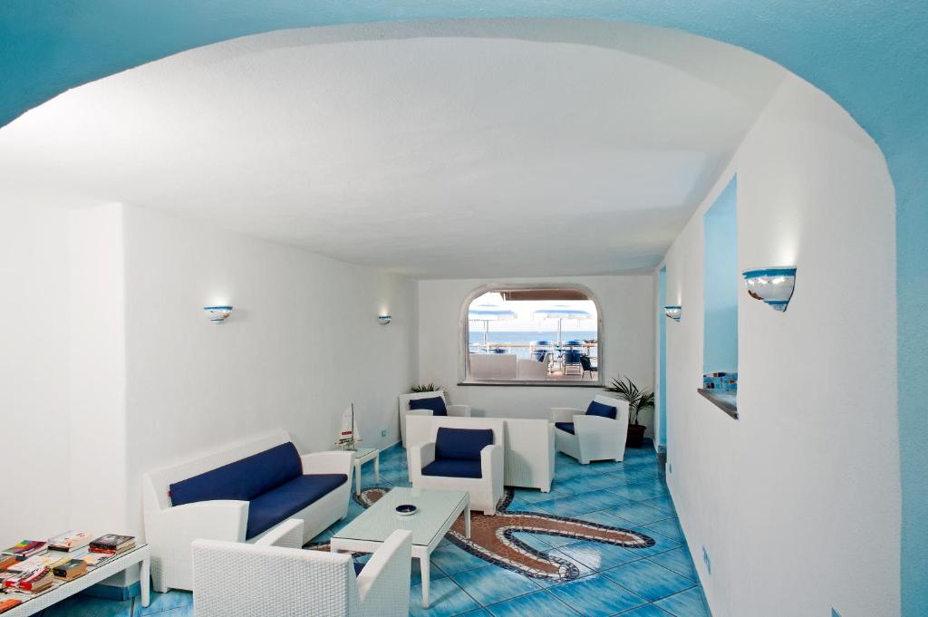 un salon avec des chaises blanches et une table dans l'établissement Residence Hotel La Rotonda Sul Mare, à Ischia