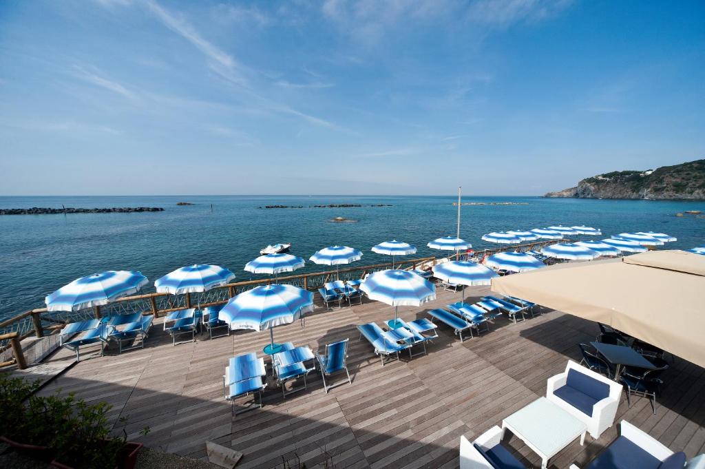 un quai avec des chaises et des parasols sur l'eau dans l'établissement Residence Hotel La Rotonda Sul Mare, à Ischia