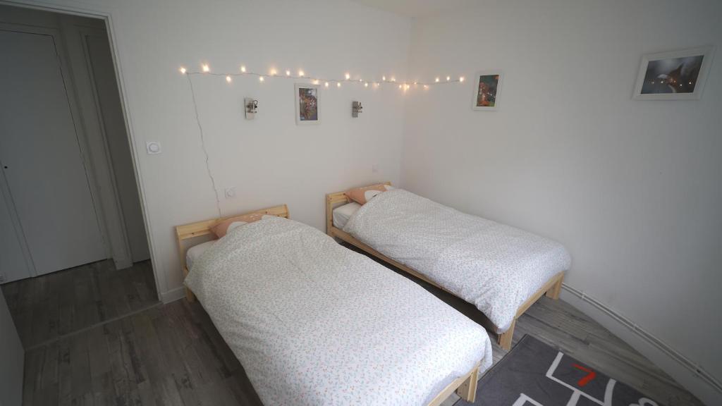 deux lits dans une chambre avec des lumières sur le mur dans l'établissement Appartement bien-être Issoire, à Issoire