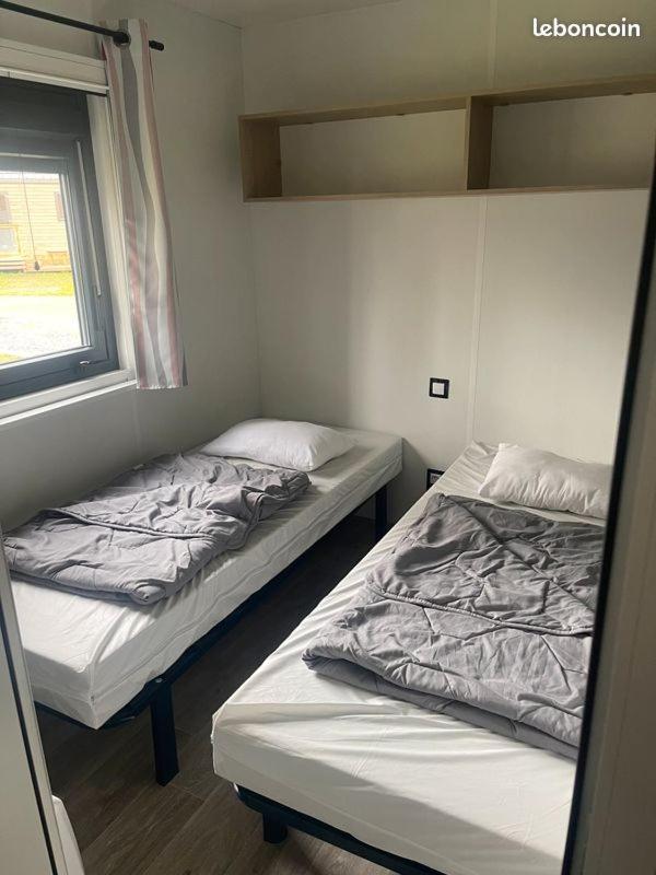 deux lits dans une petite pièce avec une fenêtre dans l'établissement Mobil Home Premium 3 ch Camping 5 Biscarrosse Mayotte F62, à Biscarrosse 11 autres photos