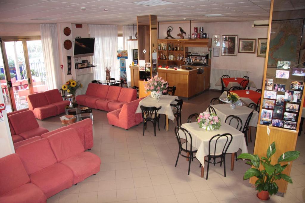 - une salle d'attente avec des tables et des canapés rouges dans l'établissement Hotel Peonia, à Rimini